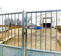 The gate leads to a courtyard with a building and containers, surrounded by trees and offices.