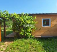 Wooden garden house with a terrace in the Gardens of Bojnice surrounded by greenery.