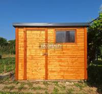 A wooden garden house in the Gardens in Bojnice surrounded by greenery under a blue sky.
