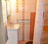 A bathroom in a 2-room apartment with a sink, shower, and ceramic tiles.