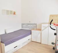 A simply furnished room with a bed, a wardrobe, and a floor with a wooden decor.