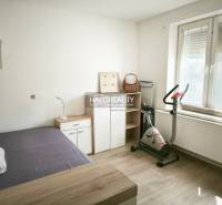 A bright room in a 2-room apartment with a wooden decor floor and an exercise bike.