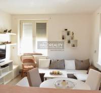 A bright living room with a TV, white furniture, and a sofa in a 2-room apartment.