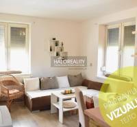 A bright living room with a sofa and a wood-patterned floor in a two-room apartment.