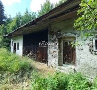 A cottage in Stará Huta surrounded by greenery with wooden elements and stone walls.