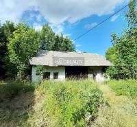 A cottage in Stará Huta surrounded by greenery under a blue sky.