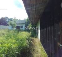 A cottage in Stará Huta with overgrown grass and a wooden wall.