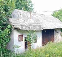 A cottage in Stará Huta surrounded by greenery, with a sloped roof and wooden elements.