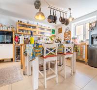 A kitchen in a family house with hanging pans, a colorful tablecloth, and modern appliances.