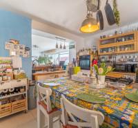 A kitchen in a family house with a colorful tablecloth and kitchen utensils on the shelves.