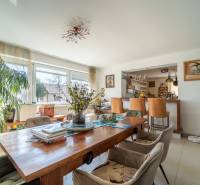 Dining area with a wooden table in a family house, decorated with flowers and plants.