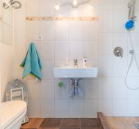 A bathroom in a family house with a shower, a sink, and white tiles.