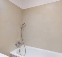 A bathroom with a bathtub and a shower in a 4-room apartment. Light tiles.