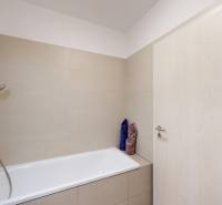 A bathroom with a bathtub and beige tiles in a 4-room apartment.