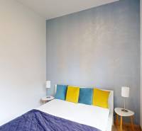 A bedroom in a 4-room apartment with colorful pillows and a wooden decor floor.