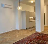 Living room with kitchen, bright interior, wooden decor flooring, hanging light fixture.