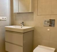 Bathroom in a 2-room apartment with a sink, cabinet, and mirror, neutral tiles.