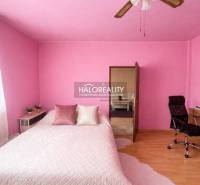 A bedroom with pink walls, a desk, and a wood-patterned floor in a family house.