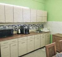 A kitchen in a family house with light furniture, a microwave, and dishes by the sink.