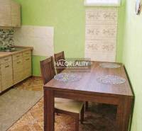 Interior of a family house with green walls, a kitchen unit, and a wooden table with placemats.
