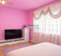 Pink bedroom in a family house with a TV, wood-patterned flooring, and curtains.