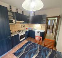 A kitchen in a 3-room apartment with blue cabinets and a dining table.