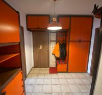 The hallway in a 3-room apartment with orange cabinets and tiled flooring.
