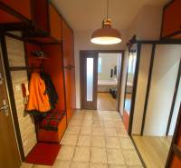 The entrance hall of a 3-room apartment with orange cabinets and tiles.