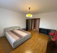 A bedroom with a double bed, wooden decor flooring, and furniture in a 3-room apartment.