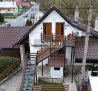 Gastro premises in Hnúšťa with an exterior staircase and a metal roof by the main road.