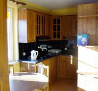 A kitchen with wooden cabinets and black tiles in a two-room apartment.
