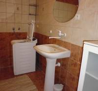 Bathroom with brown tiles, a sink, and a washing machine in a 2-room apartment.