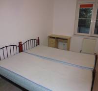 Bedroom in a 2-room apartment with two beds and a window, floor with wood decor.