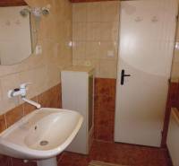 A bathroom with a sink and a mirror in a 2-room apartment, tiles in earthy colors.