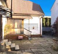 The exterior of a family house in Lučenec with a stone terrace and a gazebo.
