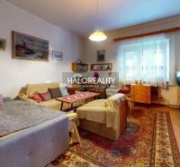 Living room in a family house with comfortable seating, decorative rugs, and a light-colored wall.