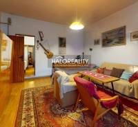Living room with a sofa and armchairs, family house with wood-patterned flooring.