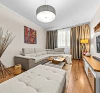 Living room in a three-room apartment with a wooden decor floor and a gray sofa.