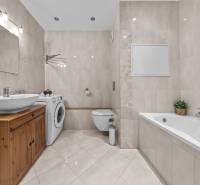 A bathroom in a 3-room apartment with a bathtub, washing machine, cabinet, and ceramic tiles.