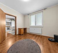 A room in a 3-room apartment with a wooden decor floor and an entrance to the kitchen.