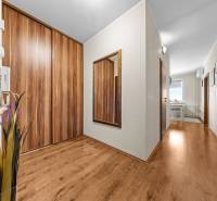 A hallway in a 3-room apartment with a wooden decor floor, a mirror, and storage space.