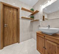 A bathroom in a three-room apartment with light tiles and wooden elements.