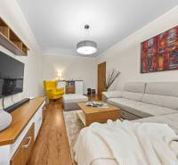 Living room in a 3-room apartment with a wooden decor floor, gray sofa, and yellow armchair.