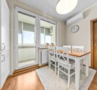 Dining area in a 3-room apartment with a wood-patterned floor and white furniture.