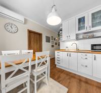 A kitchen in a 3-room apartment with white cabinets and a wooden decor floor.
