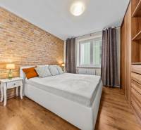 Bedroom in a 3-room apartment with a brick wall and a wooden decor floor.