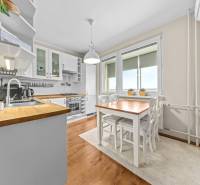 A kitchen in a 3-room apartment with white furnishings and a wooden decor floor.