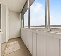 Glazed balcony with brown flooring, blind, and white walls in a 3-room apartment.