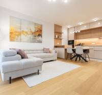 Living room with kitchen in a 2-room apartment, wooden decor flooring, cream sofa.