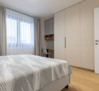 A bedroom with a bed, a wardrobe, and a wooden decor floor in a two-room apartment.